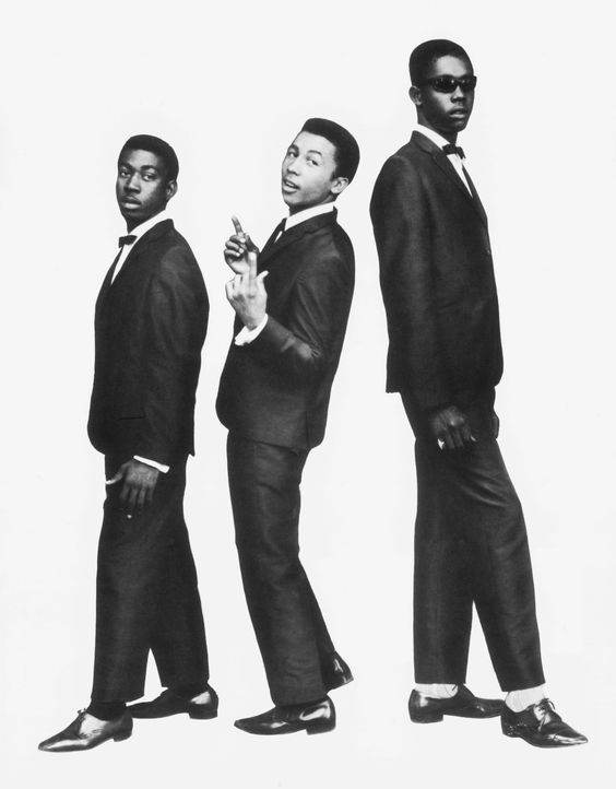 Three men in sharp black mohair suits, bow ties and winklepickers